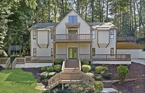 A two-story house with a front porch, a balcony on the upper floor, and a small deck in front. - 5BR & 4BA vacation home to relax, recreate or reset, and strategically located (Roswell)