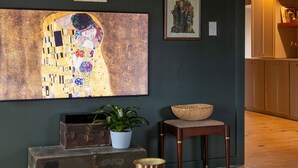 Ein Wohnzimmer mit einem großen Gemälde von Gustav Klimt, einer Uhr und einem rustikalen Holzschrank.