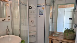 A bathroom with a large white sink, a glass shower enclosure, and a wooden vanity with a mirror.
