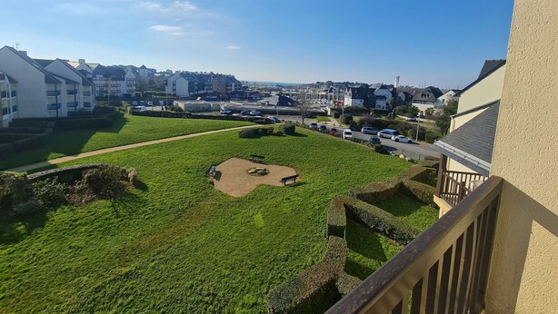 A residential area with a grassy courtyard, a paved path, and a view of a marina with boats.