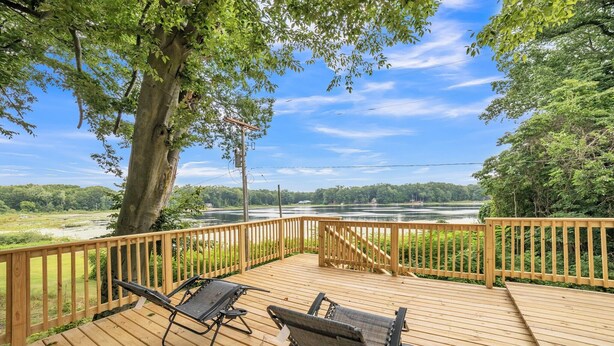 Une terrasse en bois avec deux chaises longues donnant sur une rivière.