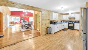 Une cuisine spacieuse dotée de planchers en bois, d’armoires blanches et d’appareils électroménagers modernes.