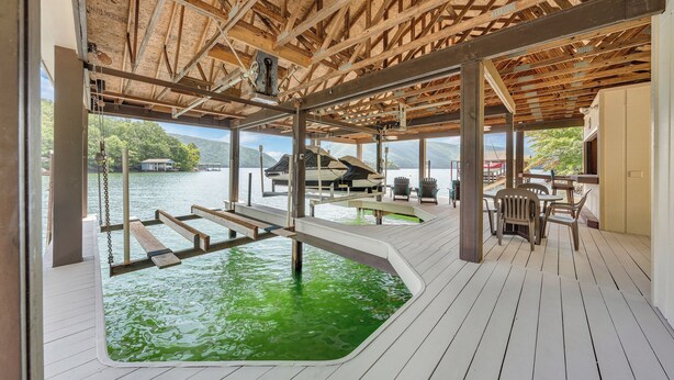 Una terraza de madera con piscina, mobiliario exterior y vista al agua.