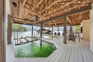 A wooden deck with a pool, outdoor seating, and a view of the water. - Lake Allure - Lakefront, Private Dock, Indoor Pool, and Hot Tub (Huddleston)