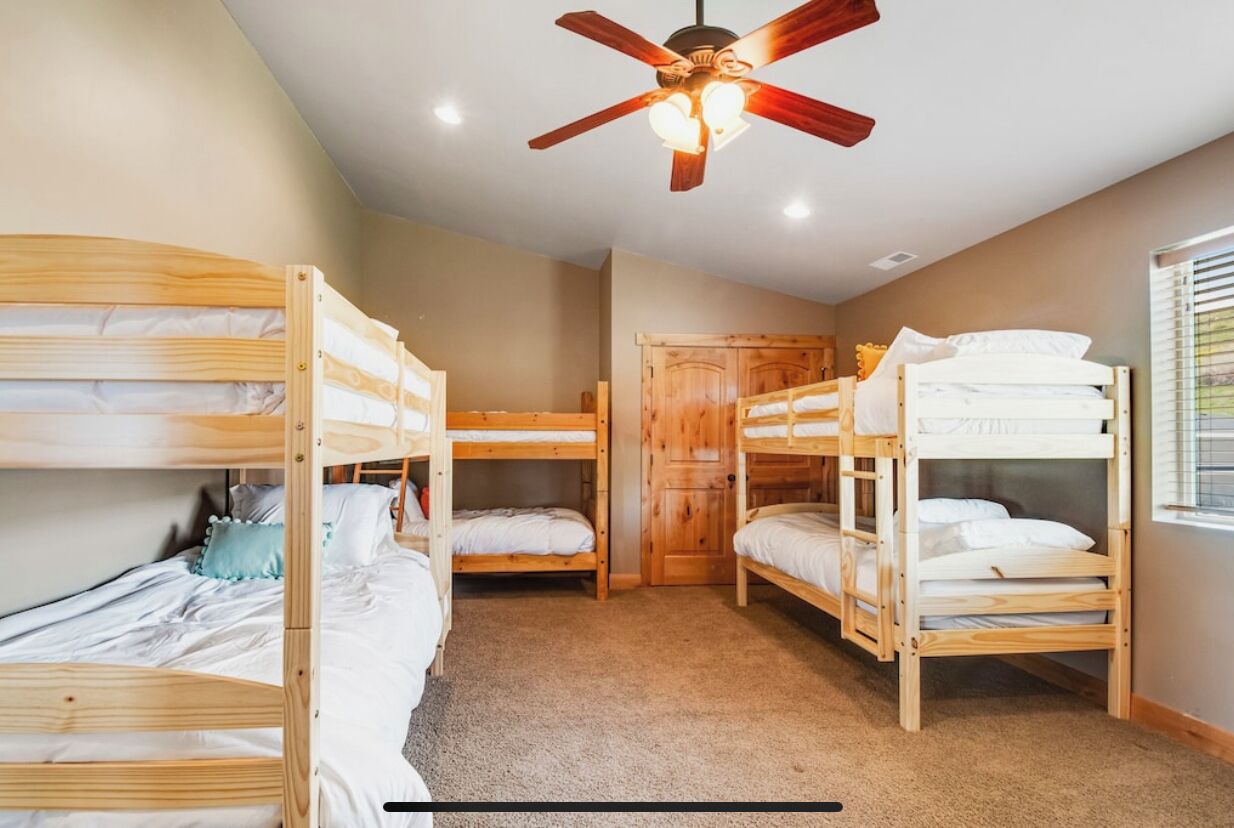 Una habitación con literas, ventilador de techo y una puerta.