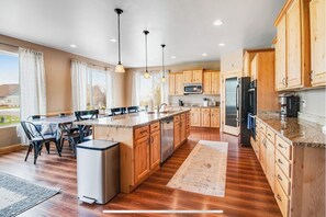 A modern kitchen with wooden cabinets, stainless steel appliances, and a dining area with a table and chairs.