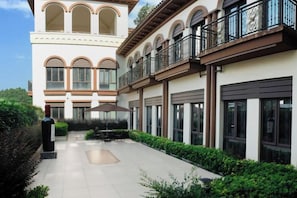A multi-story building with a courtyard, outdoor seating, and a balcony with a railing. - Tianxi Longge Hotel (Yichang)