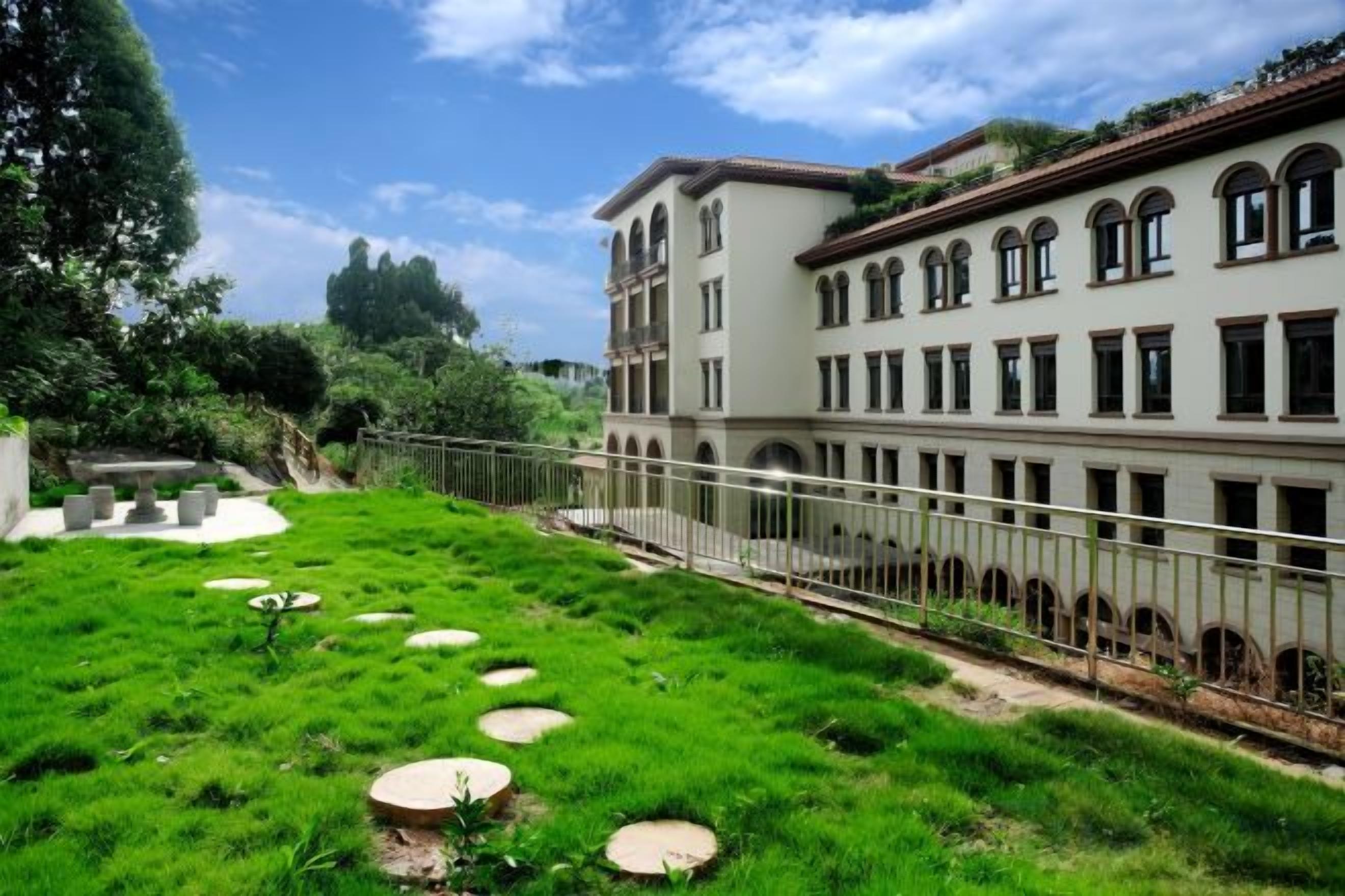 Un bâtiment doté d’une cour, d’une clôture et d’un chemin bordé de pierres circulaires servant de pas.