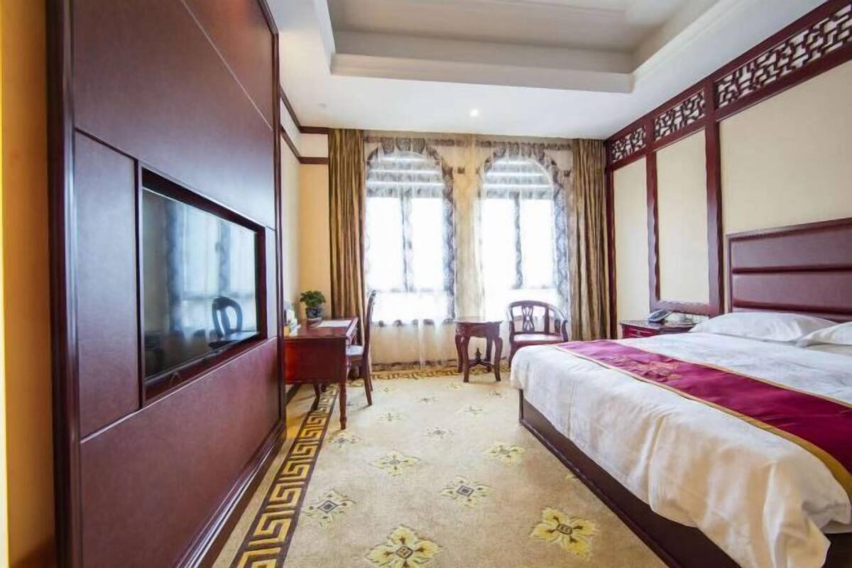 Una habitación de hotel con una cama grande, televisión, escritorio y una silla.