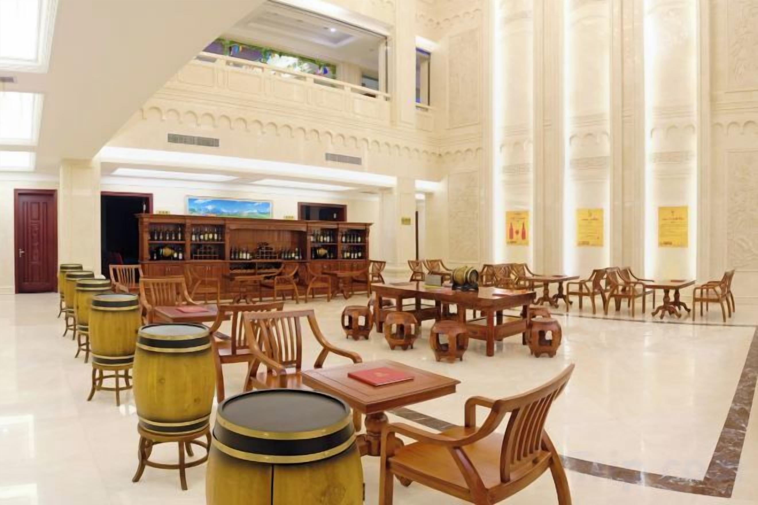 Une bibliothèque spacieuse avec de hauts plafonds, de nombreuses tables et des chaises en bois.