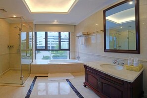 A modern bathroom with a glass shower enclosure, a large bathtub, a vanity with a mirror, and a window providing a view of the outside.