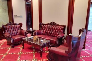 A room with two red leather armchairs, a glass coffee table, and a patterned carpet.