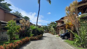 Une rue résidentielle bordée de maisons, avec un palmier et une voiture garée sur le bord.