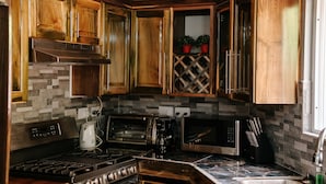 A kitchen with wooden cabinets, a gas stove, a coffee maker, and two microwaves. - TOPAZ APARTMENT VILLA -  MOUNTAIN VIEW VILLA (SOUFRIERE)