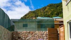A swimming pool with two purple lounge chairs, a stone wall, and a green fence. - TOPAZ APARTMENT VILLA -  MOUNTAIN VIEW VILLA (SOUFRIERE)
