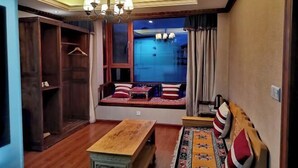 A room with a wooden bench, a table, a wardrobe, and a window seat with cushions. - Ruifeng Impressed Hotel (Shangri-La)