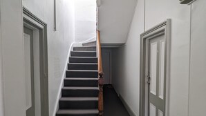 A narrow hallway with a wooden staircase leading to a landing.