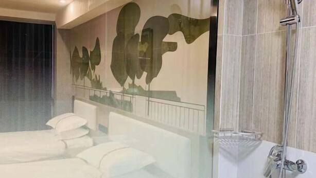 A modern bathroom with a glass shower enclosure, a white bathtub, and a decorative wall mural. - Shankee Hotel (Yangzhou Chahe University Town) (Yangzhou)
