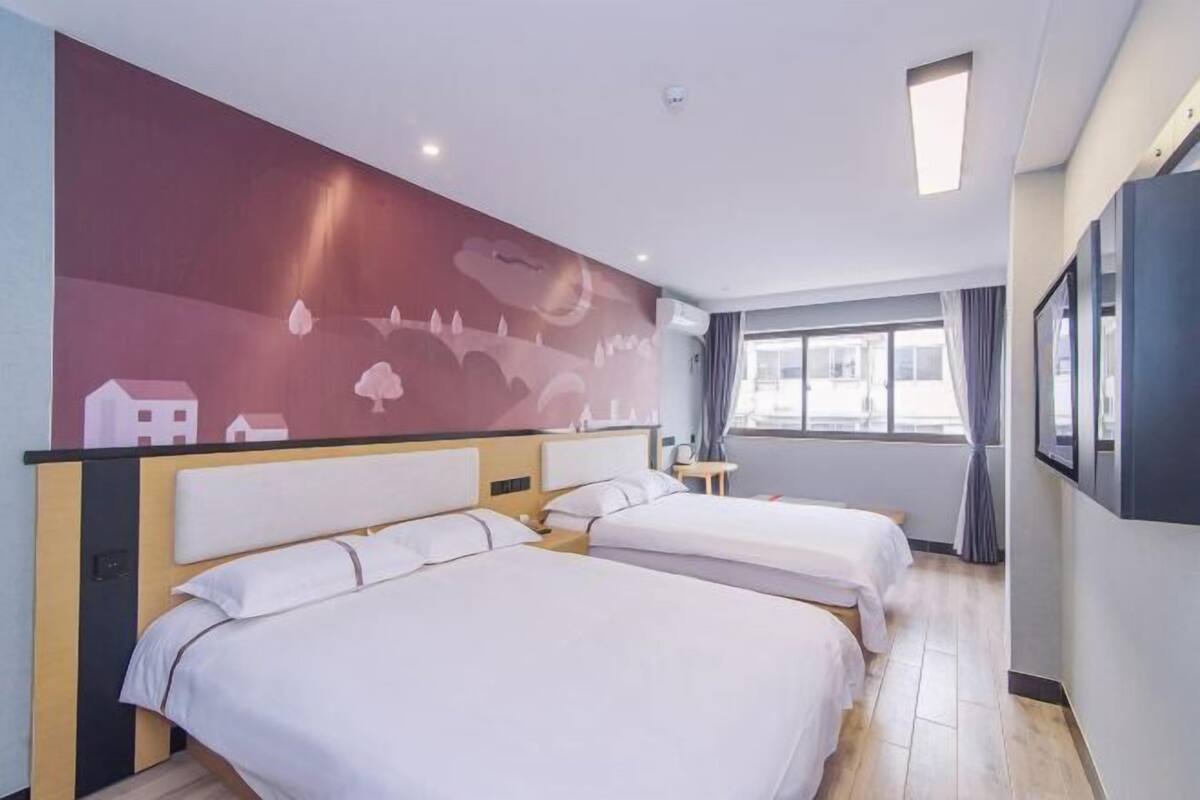 A hotel room with two beds, a large window, and a mural on the wall.