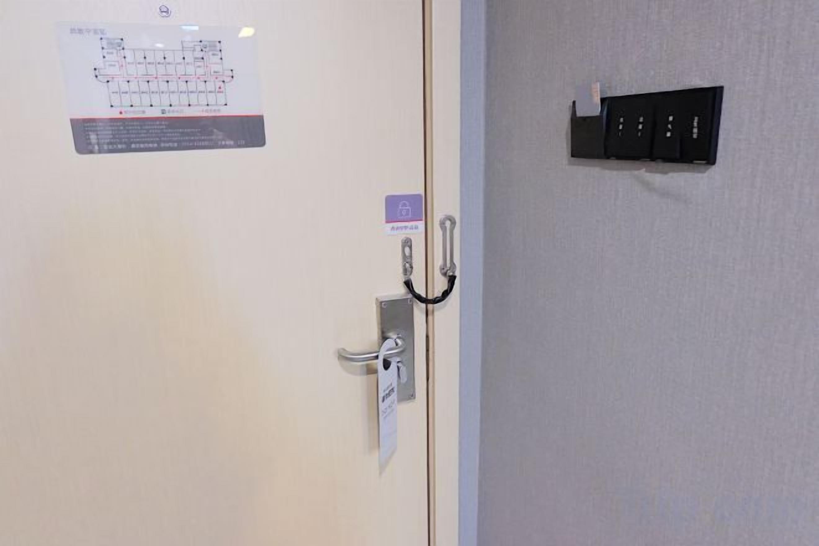 Een deur met een kaartlezer, een bord met spoedeisende instructies en een zwart object aan de muur.