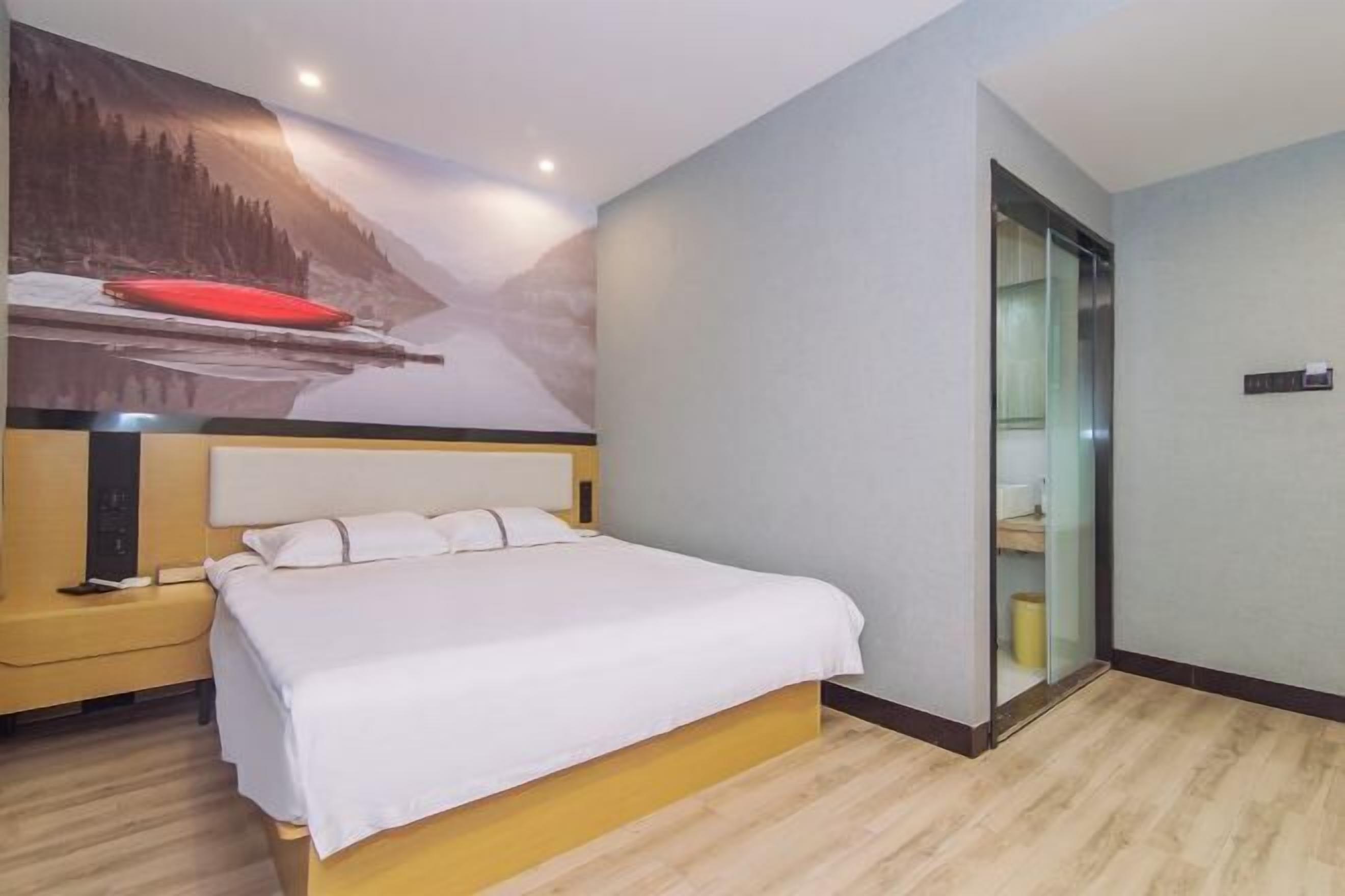 Quarto de hotel com cama, mesa de cabeceira, televisão fixada na parede e armário com porta deslizante.