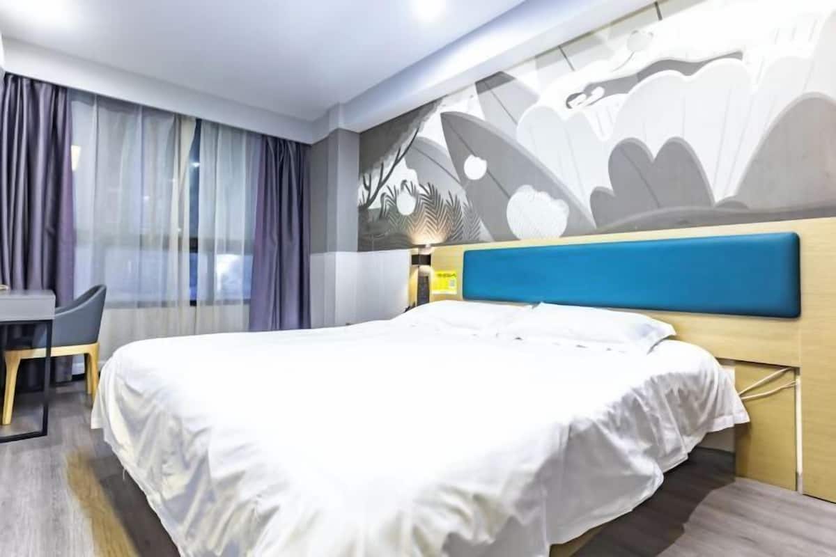 A hotel room with a bed, a desk, and a chair.