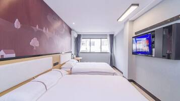 A hotel room with two beds, a TV, a window with curtains, and a wall with a floral mural.