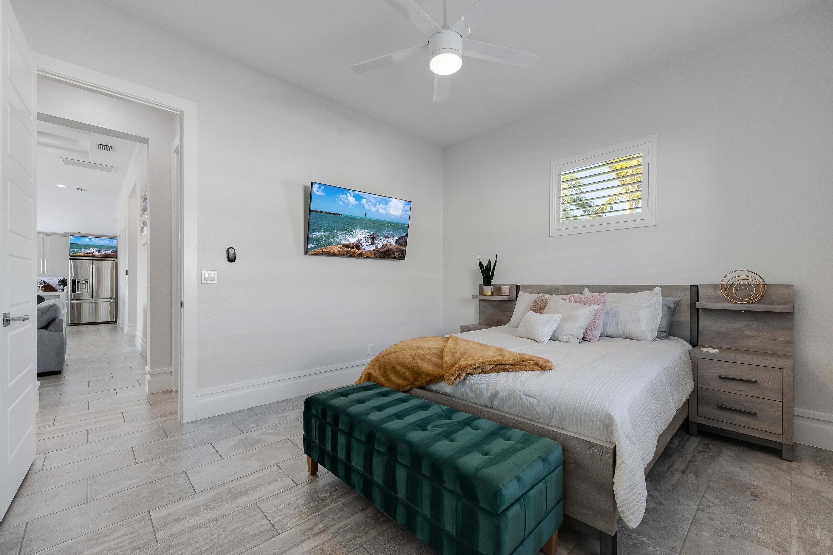 A bedroom with a bed, bedside table, and a view of the ocean.