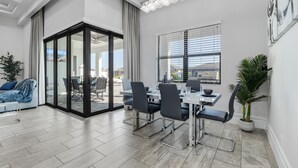 Un comedor moderno con un separador de vidrio, una mesa con sillas y vistas al exterior.