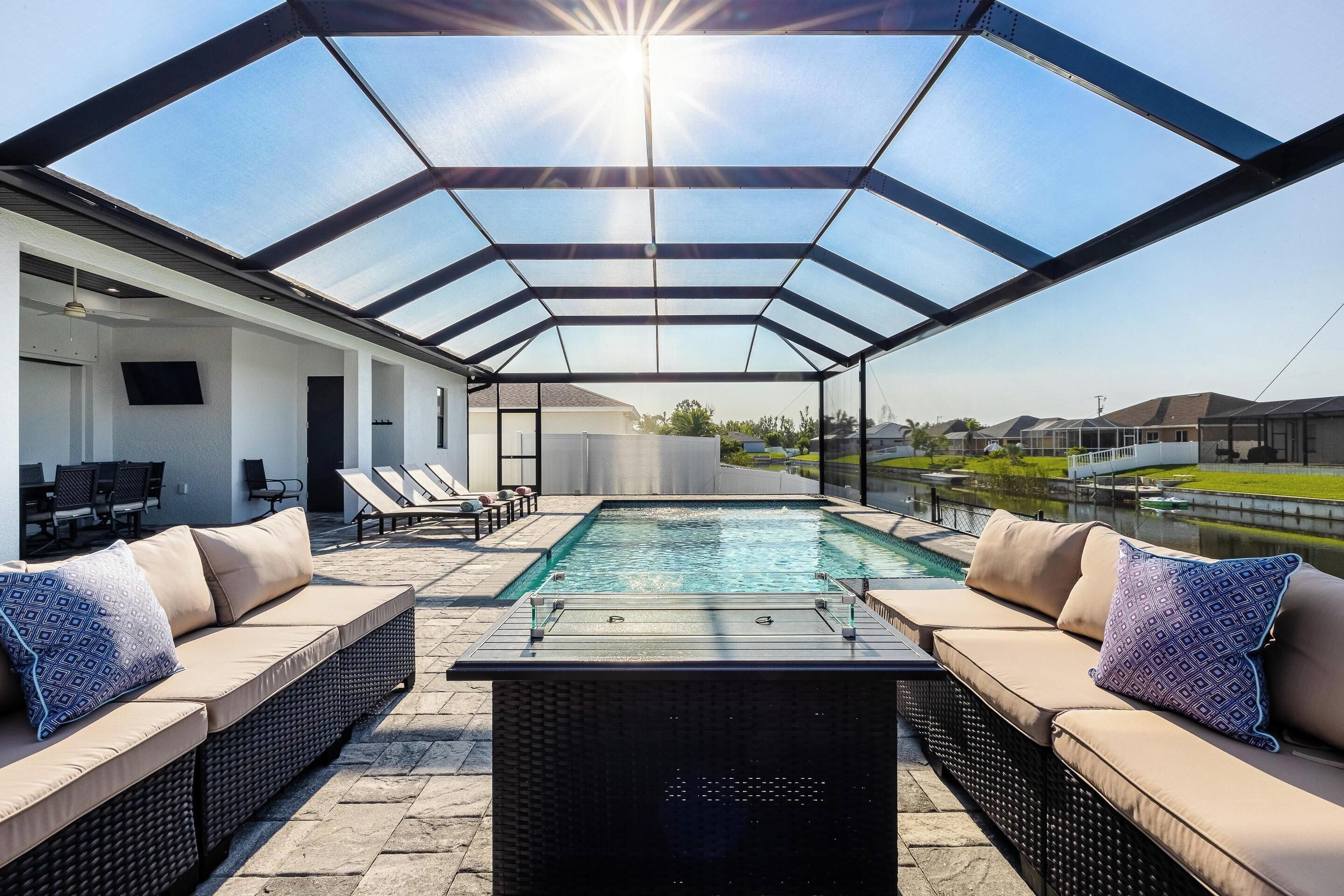 A covered outdoor area with a pool, lounge seating, and a pergola structure.