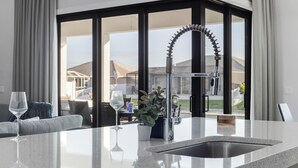 Cocina moderna con una isla grande, pileta de acero inoxidable y vista del patio exterior a través de amplios ventanales.