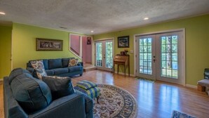 Ein geräumiges Wohnzimmer mit einem blauen Sofa, einem gemusterten Teppich und einer Treppe, die zu einer weiteren Ebene führt.