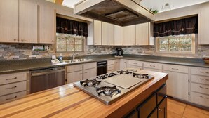 Una cucina moderna con isola centrale, elettrodomestici integrati e ampie finestre.