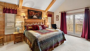 Una camera accogliente con una testiera in legno, un letto grande con una coperta colorata, un comodino con una lampada e una finestra con tende.