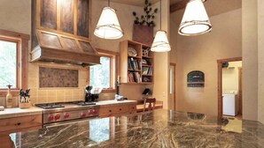 Une cuisine spacieuse dotée d’un grand plan de travail en marbre, de meubles de rangement en bois et d’une cuisinière encastrée.
