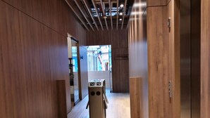 Un interior moderno con paneles de madera, una columna central y un ascensor.