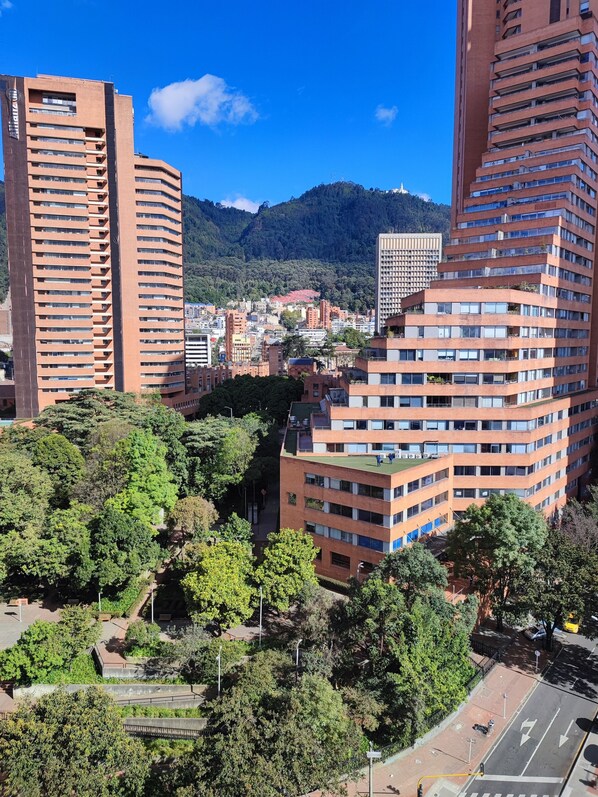 A high-rise building with multiple floors, surrounded by greenery and other buildings.