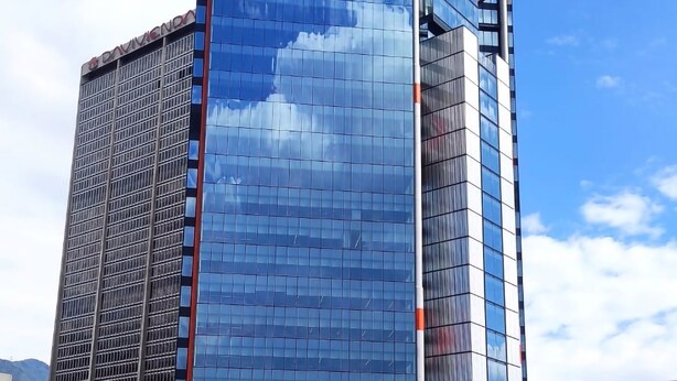 Un moderno edificio de gran altura con ventanas de vidrio reflectante y un letrero llamativo en la parte superior.