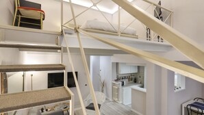 A multi-level interior with a staircase, a sofa, a dining area, and a kitchen. - Giglio Bianco Apartment (Firenze)