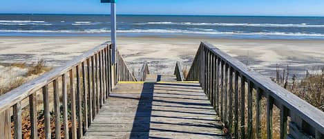 A wooden boardwalk leading to a beach with a sign reading "SHADE".