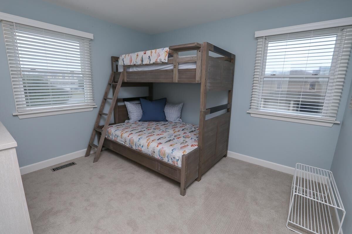 A bunk bed with a ladder, a patterned bedspread, and pillows.