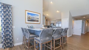 A modern kitchen with a central island, bar stools, and a dining area. - Baliwest - Gorgeous 5 BR Oceanfront home with a panoramic ocean view! (Southern Shores)