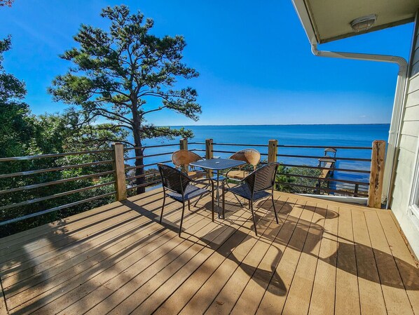 A wooden deck with a table and chairs overlooking a body of water.
