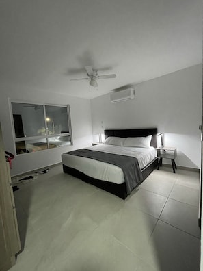 Relax in this serene bedroom with a large bed, bedside tables, and a ceiling fan above.