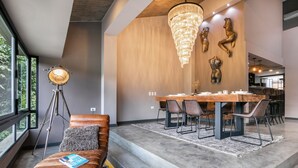 Ein moderner Essbereich mit Holztisch und Stühlen, einer Chandelüster und einer Bank mit einem Buch.
