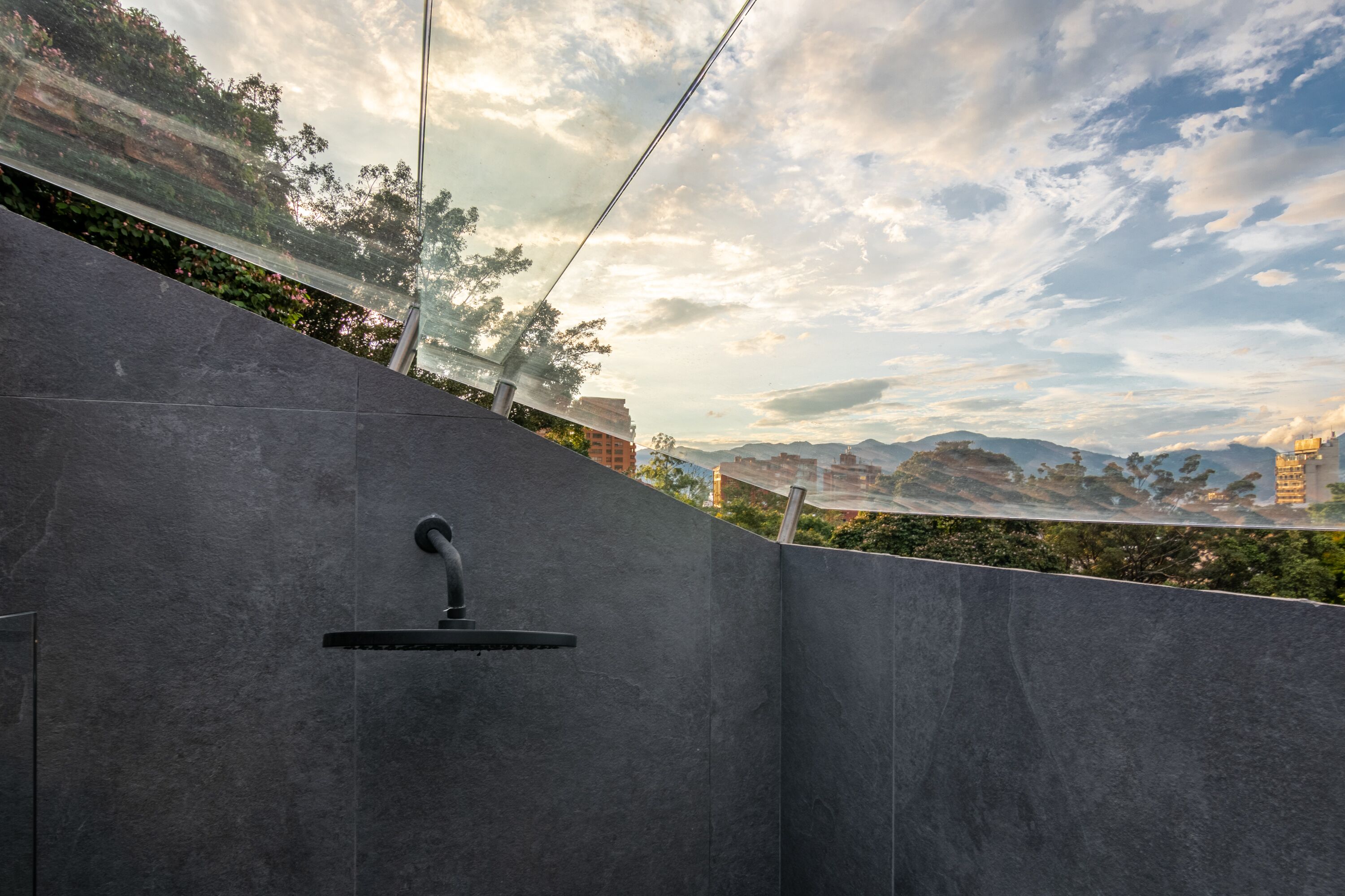 A modern outdoor shower area with a view of a cityscape and mountains in the background.