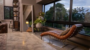 A modern living room with a leather recliner, a tall plant, and a bookshelf.