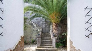 A stone staircase leading up to a door, flanked by white walls with black decorative elements. - Codolar – Panoramic Views, Terrace & Parking (Tossa De Mar)