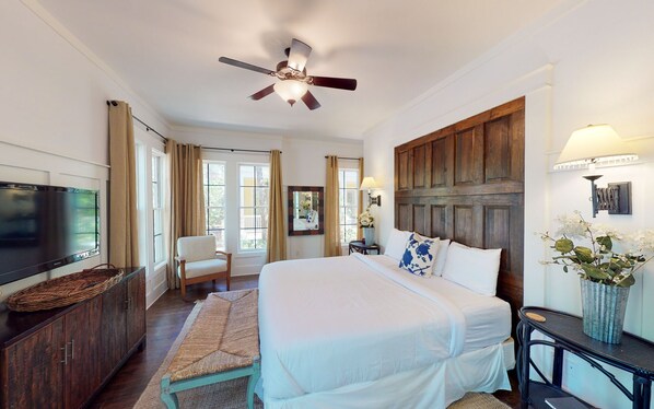 A hotel room with a large bed, a ceiling fan, a TV, a desk with a lamp, and a view of the outdoors. - WaterColor Park District - Private beach access & amenities! (Santa Rosa Beach)