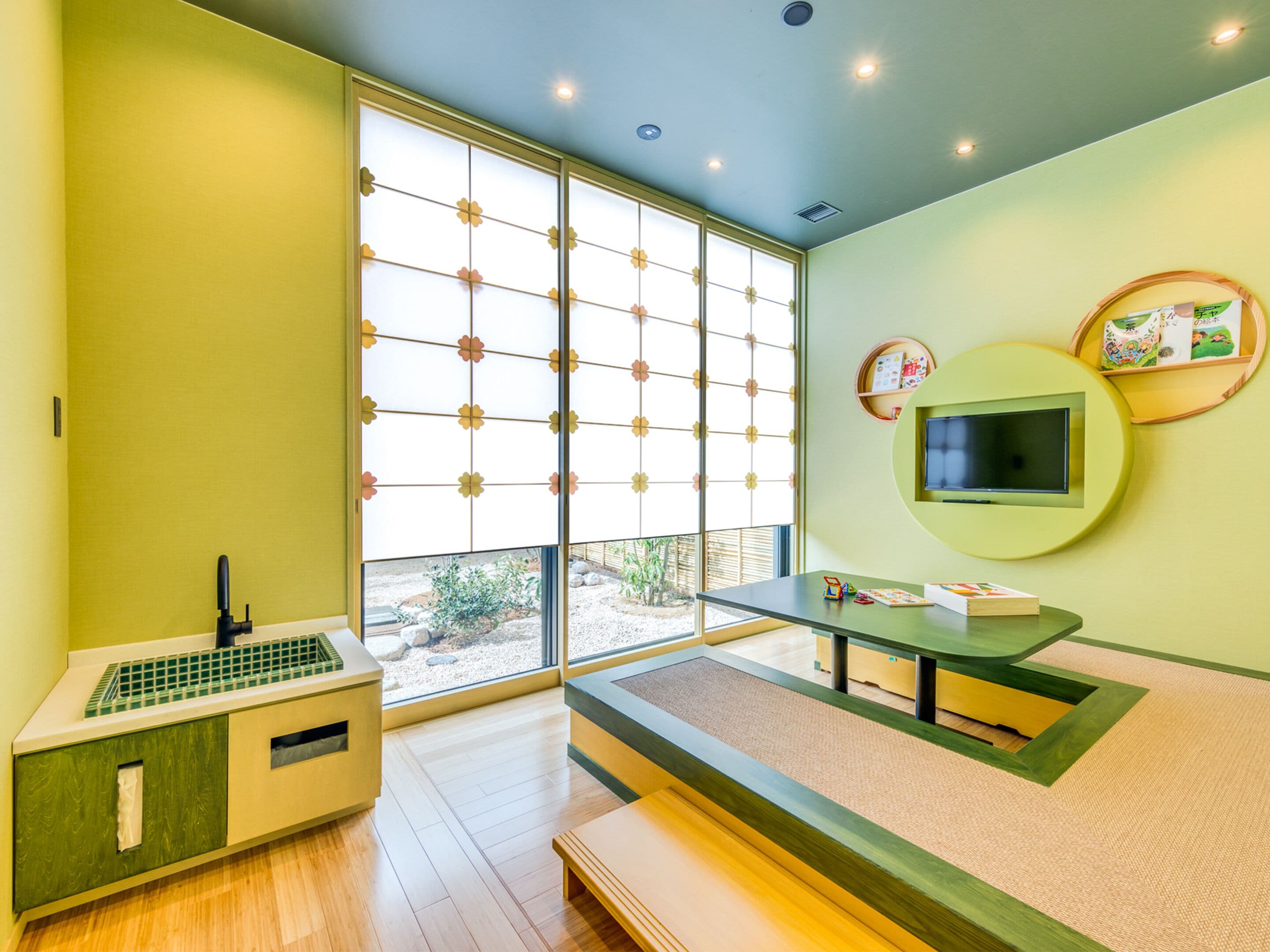 A modern room with a large sliding shoji screen, a TV mounted on a circular wooden frame, and a small wooden table with a bench.